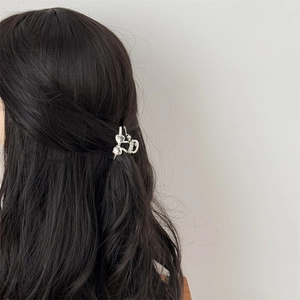 Detail of a sparkling silver rhinestone bow hair clip styled on a brunette ponytail
