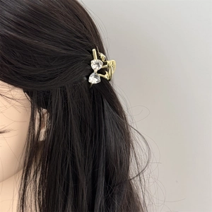 Detail of sparkling rhinestone bow hair claw clip in champagne gold on a model
