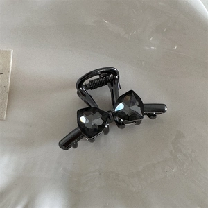 Detailed close-up of a mini black alloy hair claw clip with grey crystal bow decor