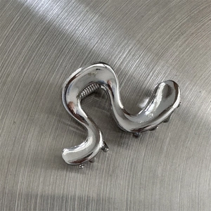 Détail d'une pince à cheveux ondulée style argent liquide avec finition chromée miroir