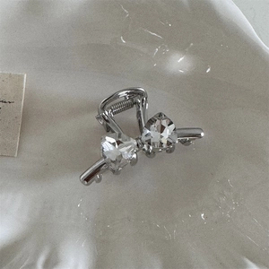 Detailed view of silver bow-knot hair claw clip with sparkling heart-shaped crystals
