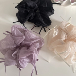 Detail showing sheer organza scrunchies in black, lilac, and cream with ribbon bows