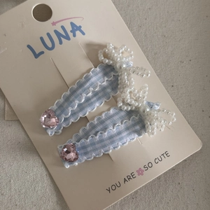 Detailed view of light blue plaid hair clips with pink heart crystals and pearl bows