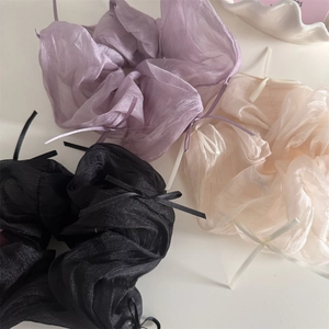 Detailed macro view of chiffon scrunchies in purple, white and black with bow ribbons