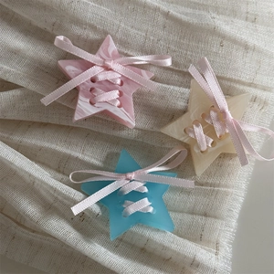 Close-up of three star hair clips with marble texture and pink ribbon bow details
