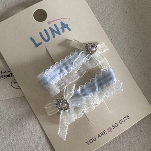 Detail of blue plaid hair clips with lace edges and heart-shaped rhinestones
