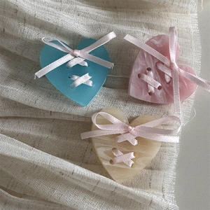 Detailed view of heart-shaped hair clips with criss-cross pink ribbons and bow accents