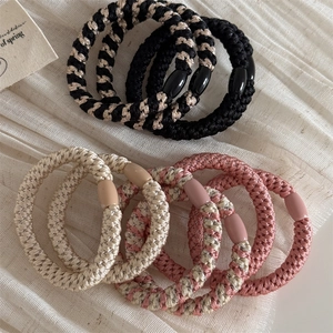 Set of durable woven elastic hair ties in black, champagne, and rose pink on fabric