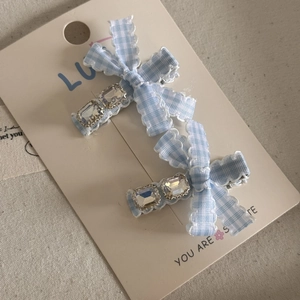 Close-up of blue gingham bow hair clips with sparkling rhinestones on display card