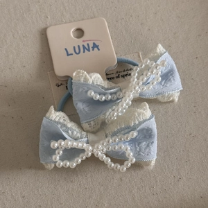 Detail of light blue plaid bow hair clips with pearls and lace trim on linen background