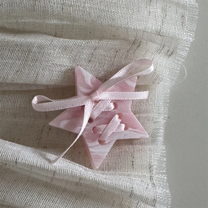 Macro detail of cream star hair clip with marble resin texture and pink silk ribbon bow