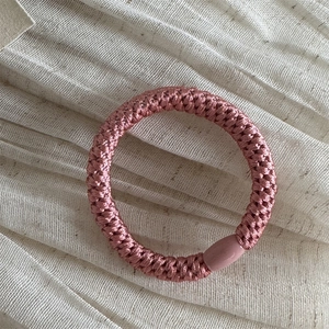 Detail of pink woven elastic hair tie with high-stretch fiber and metallic luster