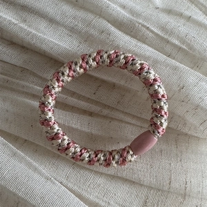 Detail of pink and beige spiral hair tie showing durable woven fabric and plastic buckle