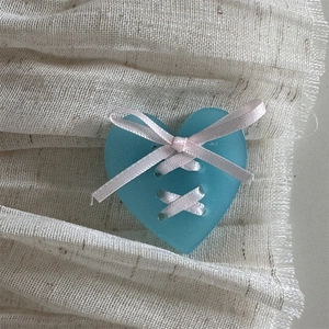Detail shot of blue heart ornament with pink ribbon corset tie and a cute bow
