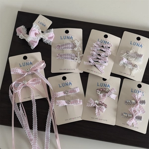 Rosa kariertes Haarspangen-Set mit Strass und Perlen auf dunklem Holzhintergrund