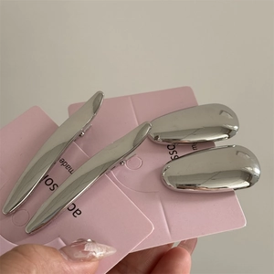 Détail de barrettes Y2K argentées et pinces goutte d'eau sur carte rose
