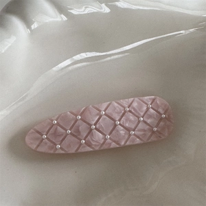 Close-up of pink quilted duckbill hair clip with mini pearls and marble texture