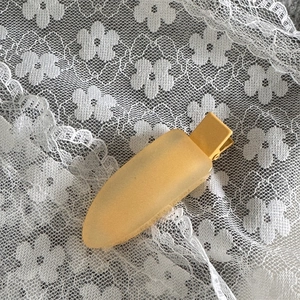 Gros plan d'une pince à cheveux jaune mat sur fond de dentelle blanche avec lumière douce