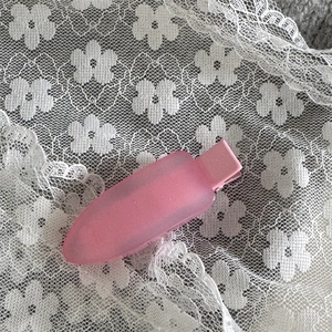 Gros plan sur la barrette mate rose bonbon sur un fond de dentelle blanche élégante