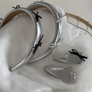Close-up of silver bow headbands and hair clips on a white textured fabric background