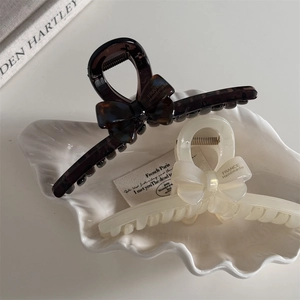Détail de pinces à cheveux en acétate avec nœud 3D en motif écaille et crème