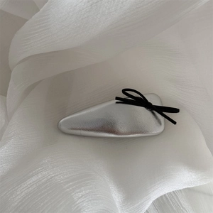 Close-up of silver leather headband with a black bow knot on white tulle background