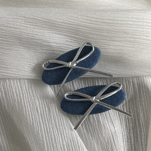 Λεπτομέρεια από τσιμπιδάκια μαλλιών denim με ασημένιους φιόγκους σε λευκό φόντο