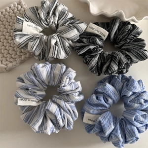 Detailed macro view of four striped cotton fabric scrunchies with handmade labels