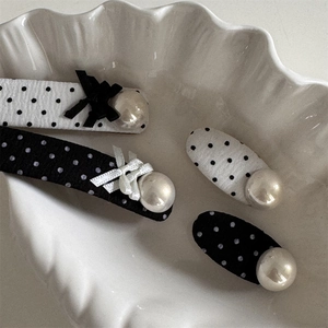 Chic polka dot hair clips set with pearls and bows on a white decorative tray