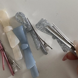 Detail showing various acetate bow hair clips in pink, beige, blue and glitter finishes
