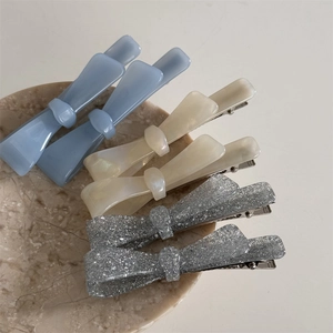 Set of 6 acetic acid bow hair clips in blue, beige, and silver on a marble tray