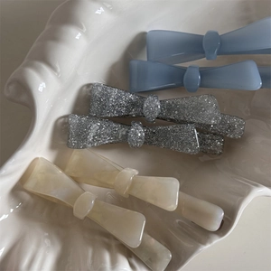 Detail of bow hair clips in light blue matte, silver glitter and cream pearl finishes