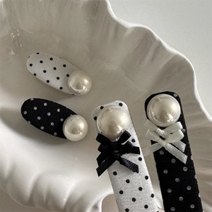 Polka dot hair clips set with pearls and bows on a white ceramic shell plate