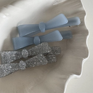 Set of four bow hair clips in matte misty blue and silver glitter on white shell tray