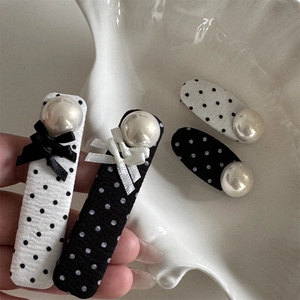 Detailed set of four black and white polka dot hair clips with pearls and bows