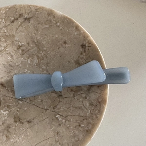 Detailed macro view of the elegant blue acetate bow hair clip on a marble texture plate