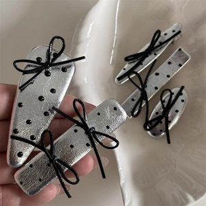 Detailed close-up of silver polka dot leather hair clips with black bows in various shapes