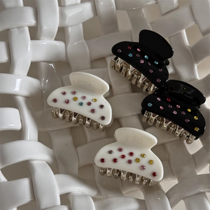 Dettaglio di quattro piccole mollette per capelli con strass colorati in nero e panna