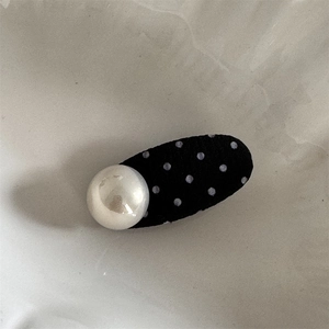 Detail of cute polka dot hair clip with large faux pearl on a black fabric base