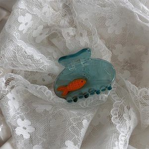 Dettaglio del fermaglio per capelli acquario blu trasparente con pesce arancione