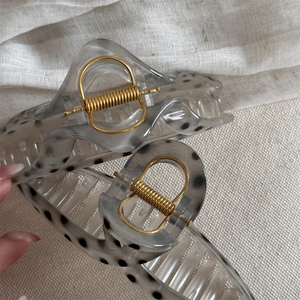Translucent grey hair claw clip with black polka dots and gold metal spring accents
