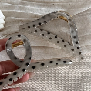 Close-up of translucent grey polka dot hair claw clip with a strong gold metal spring