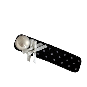 Polka dot fabric hair clip with a large pearl and a white ribbon bow on white background