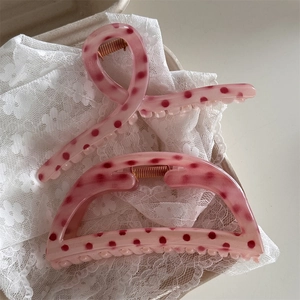Detailed macro view of pink polka dot hair claw clips on white lace fabric material