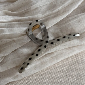 Detailed macro view of gray polka dot acetate triangle hair claw with gold spring