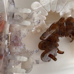 Macro detail of large acetate claw clips showing elegant marble patterns and spring hinge