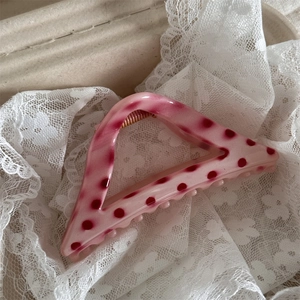 Close-up of pink semi-circle hair claw with red polka dots on elegant lace fabric