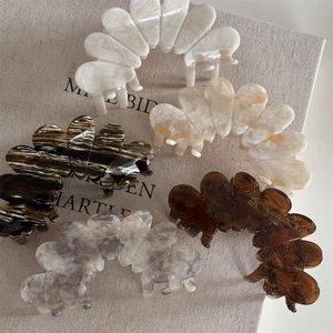 Detailed top view of 5 acetate flower hair claw clips in marbled colors on beige linen