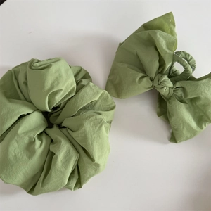 Detail of light green fabric bow hair claw clip and ruffled scrunchie set for women