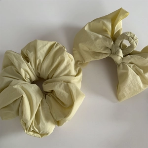 Detail of light yellow bow claw clip and scrunchie set in crinkled fabric texture